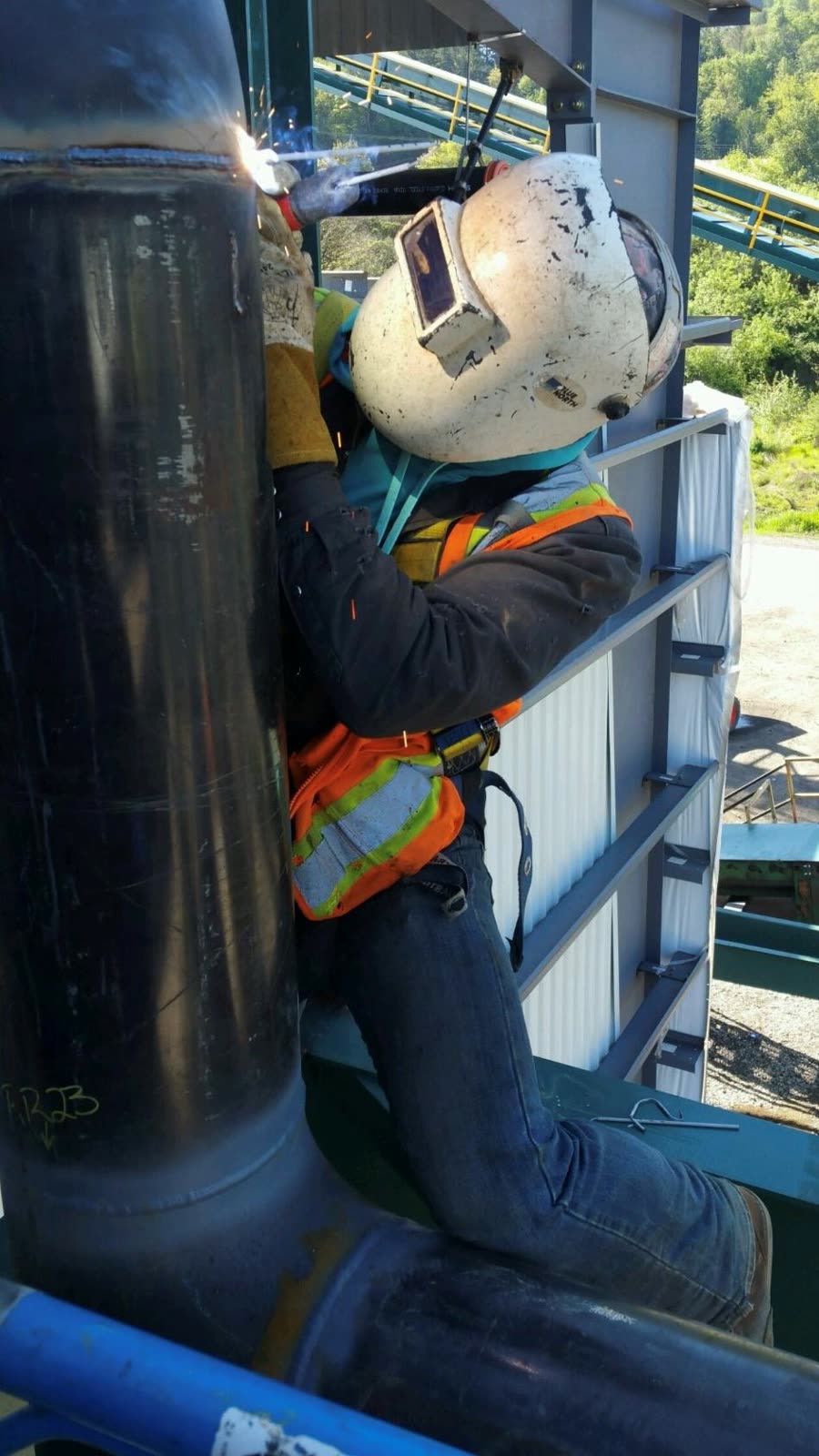 A SWAT welder in a hard-hat welding helmet working on a large vessel